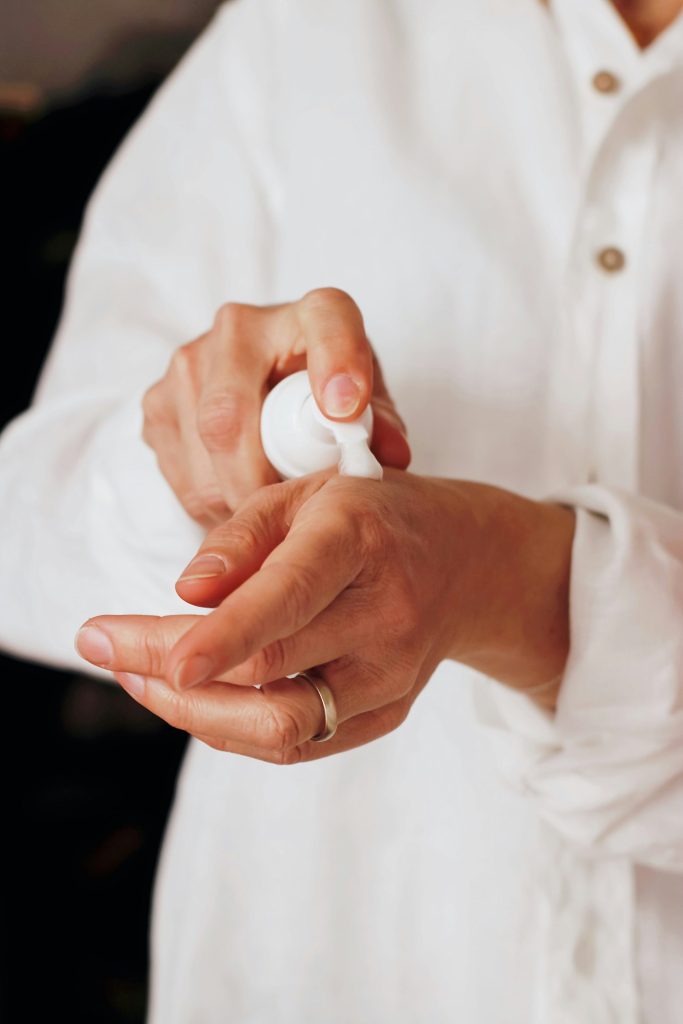 hands applying lotion from white pump